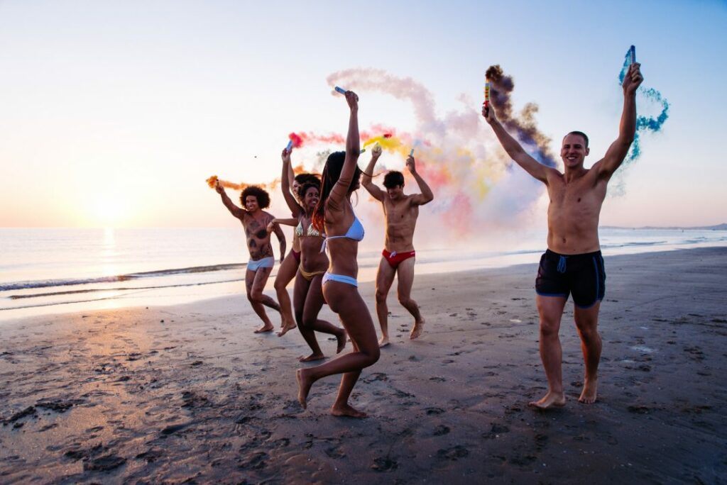 group-of-friends-having-fun-running-on-the-beach-with-smoke-bombs.jpg